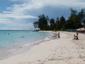A picturesque sandy beach featuring fine sand and tranquil waters, perfect for relaxation and leisure activities.
